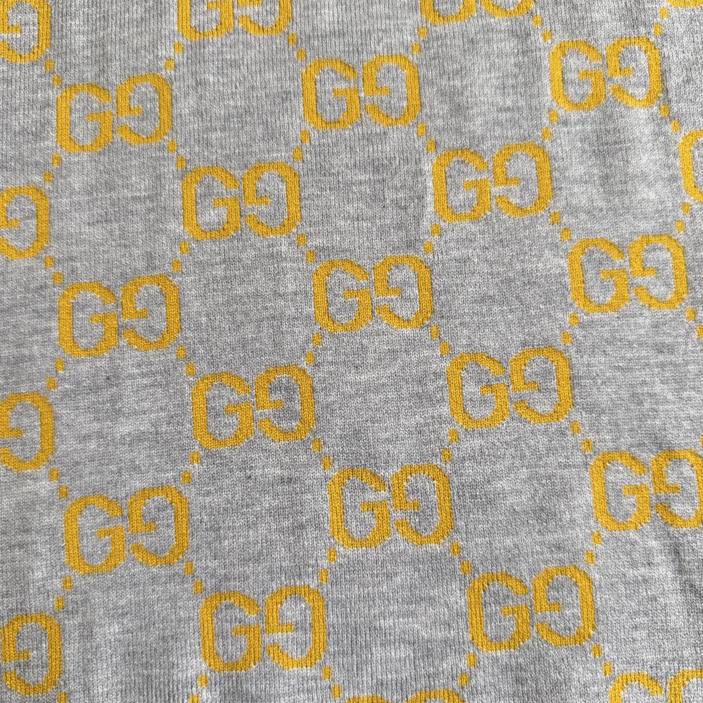 Close-up of heather gray knit fabric with repeating yellow GG logo pattern