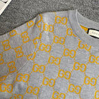 Heather gray long-sleeve sweater with yellow GG logo pattern and ribbed cuffs