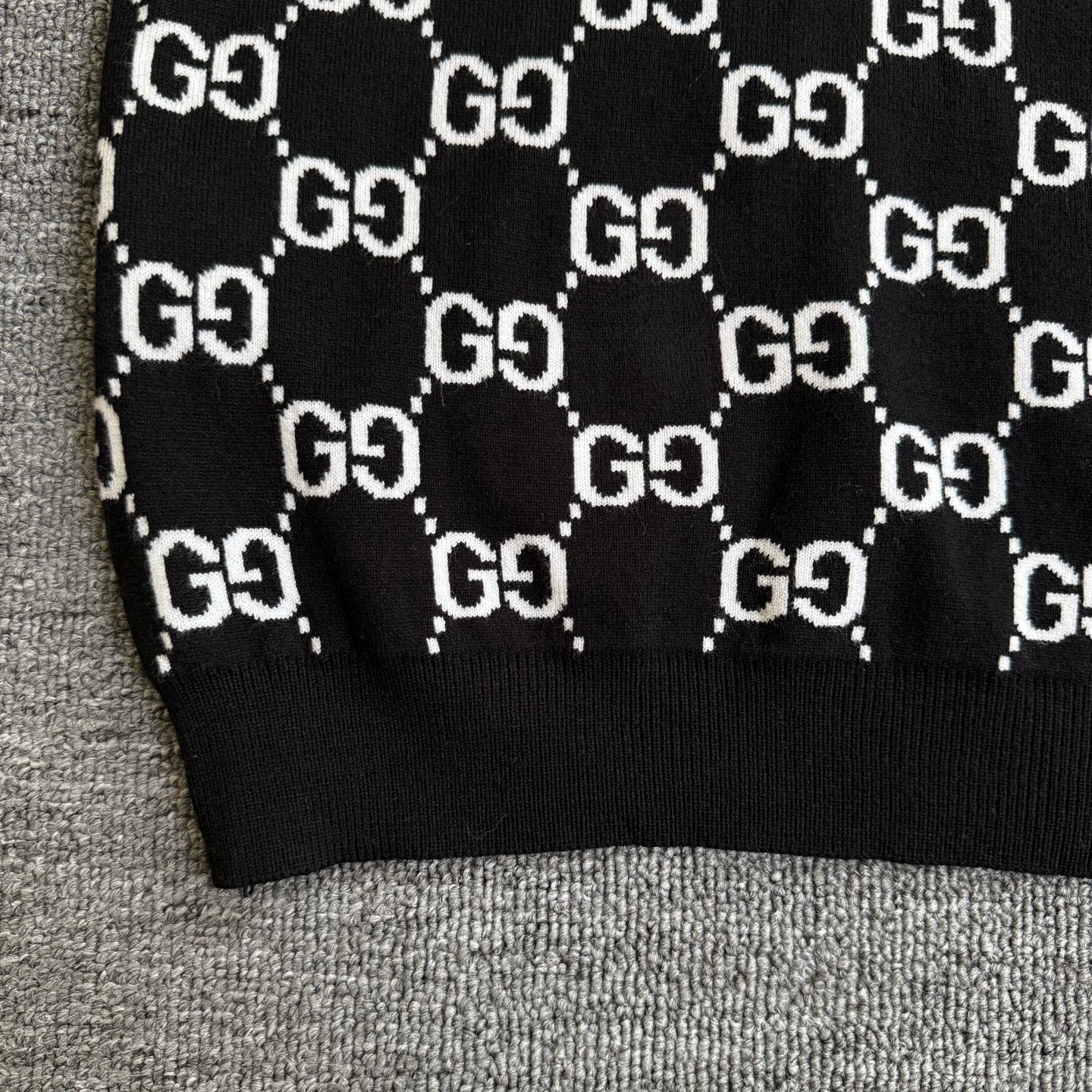 Black knit sweater hem with repeating white GG logo lattice pattern