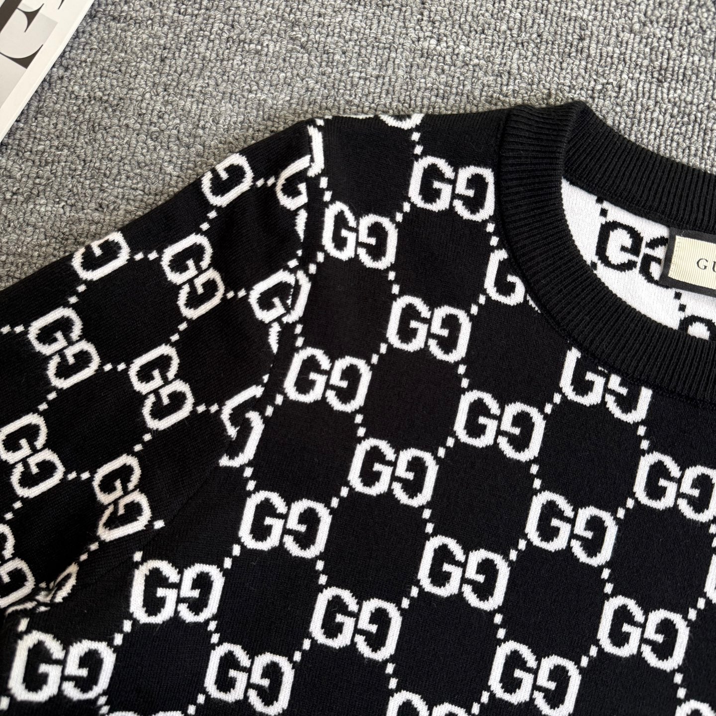 Black knit sweater with white outlined GG logo lattice pattern