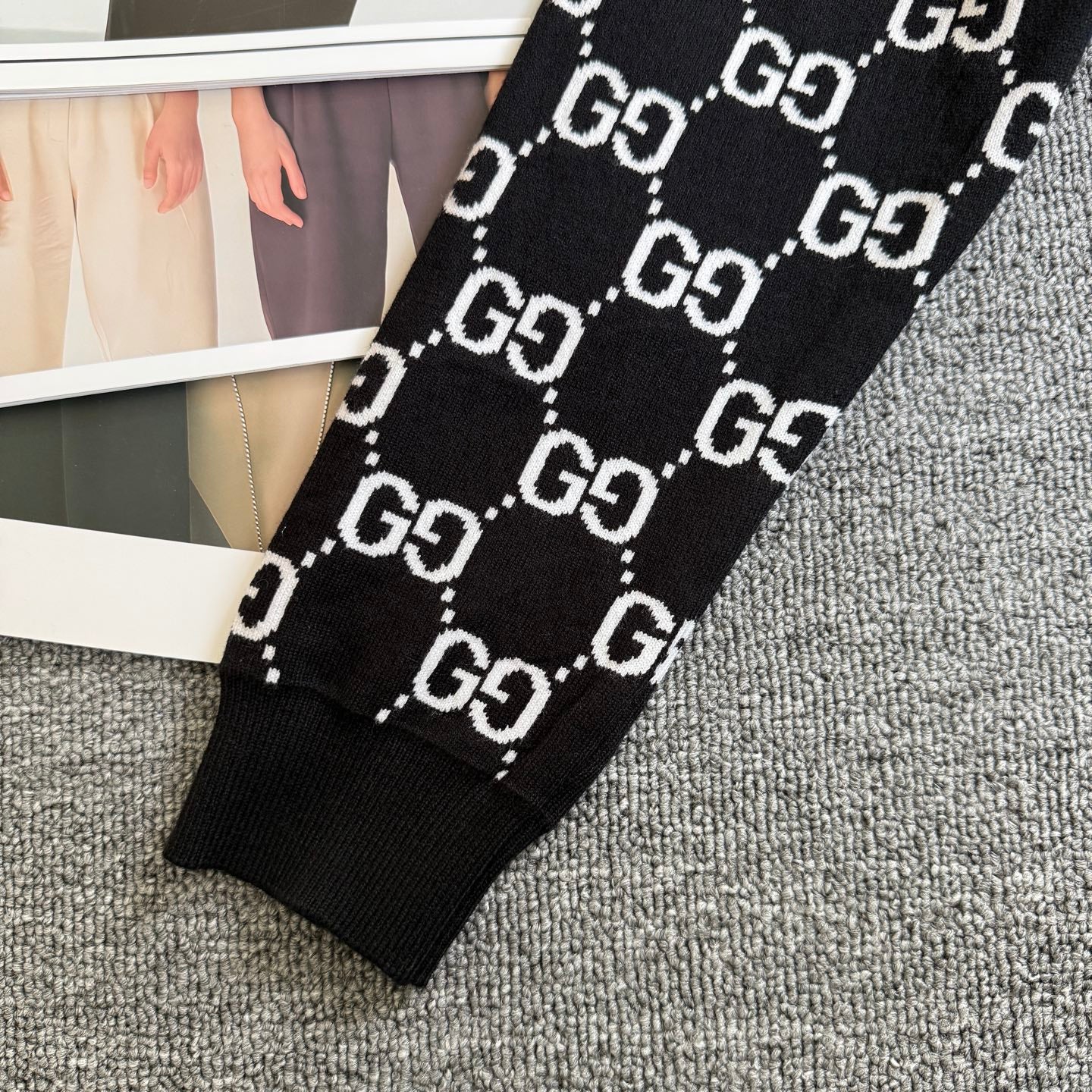 Black knit sweater sleeve with ribbed cuff and repeating GG logo lattice pattern
