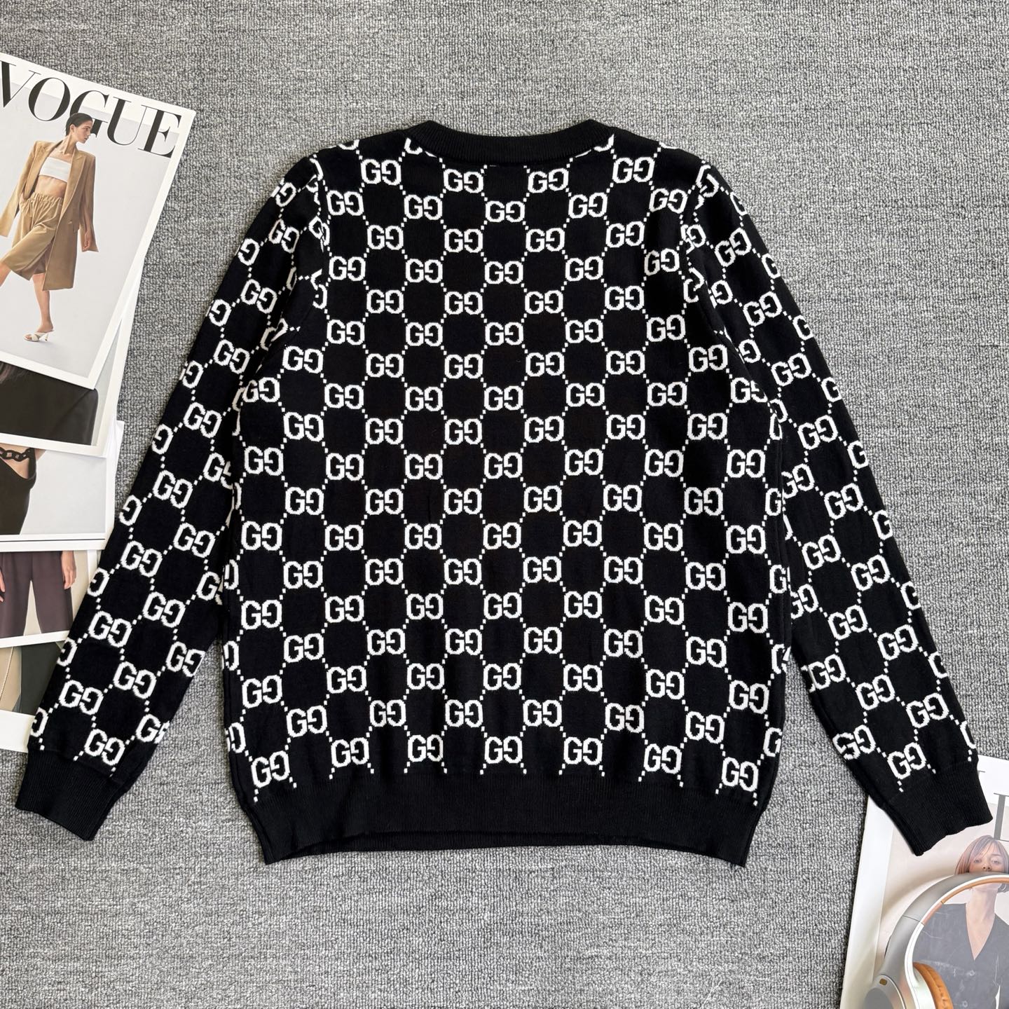 Black knit sweater with repeating white GG logo lattice pattern and ribbed cuffs