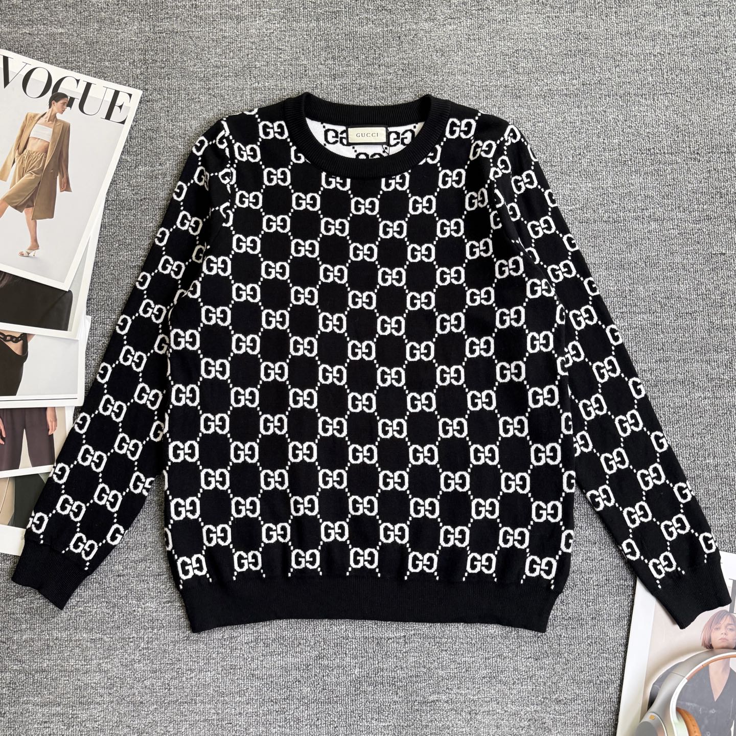 Black knit sweater with repeating white GG logo lattice pattern and ribbed crew neck