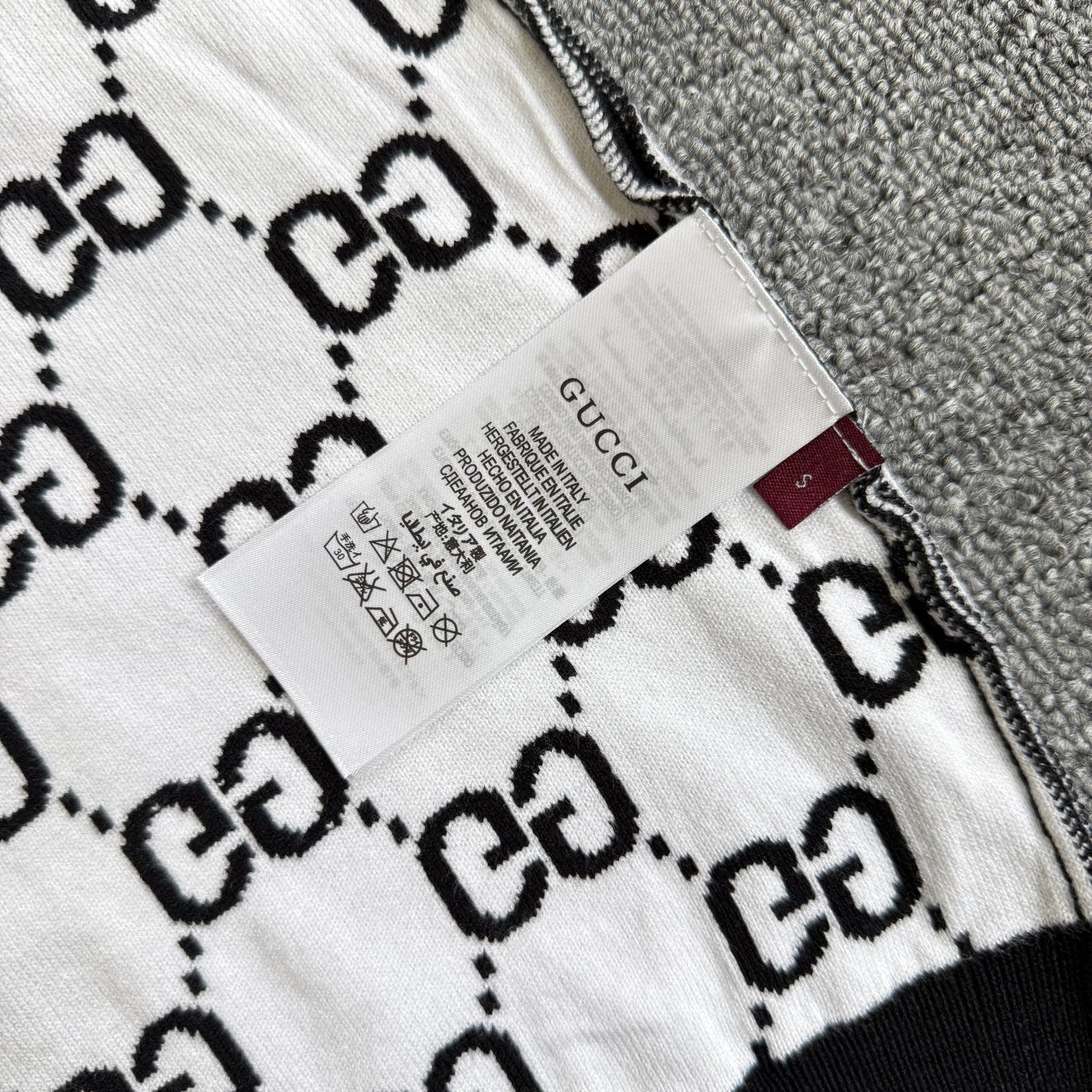 Gucci label and care tag on white-and-black GG logo knit top