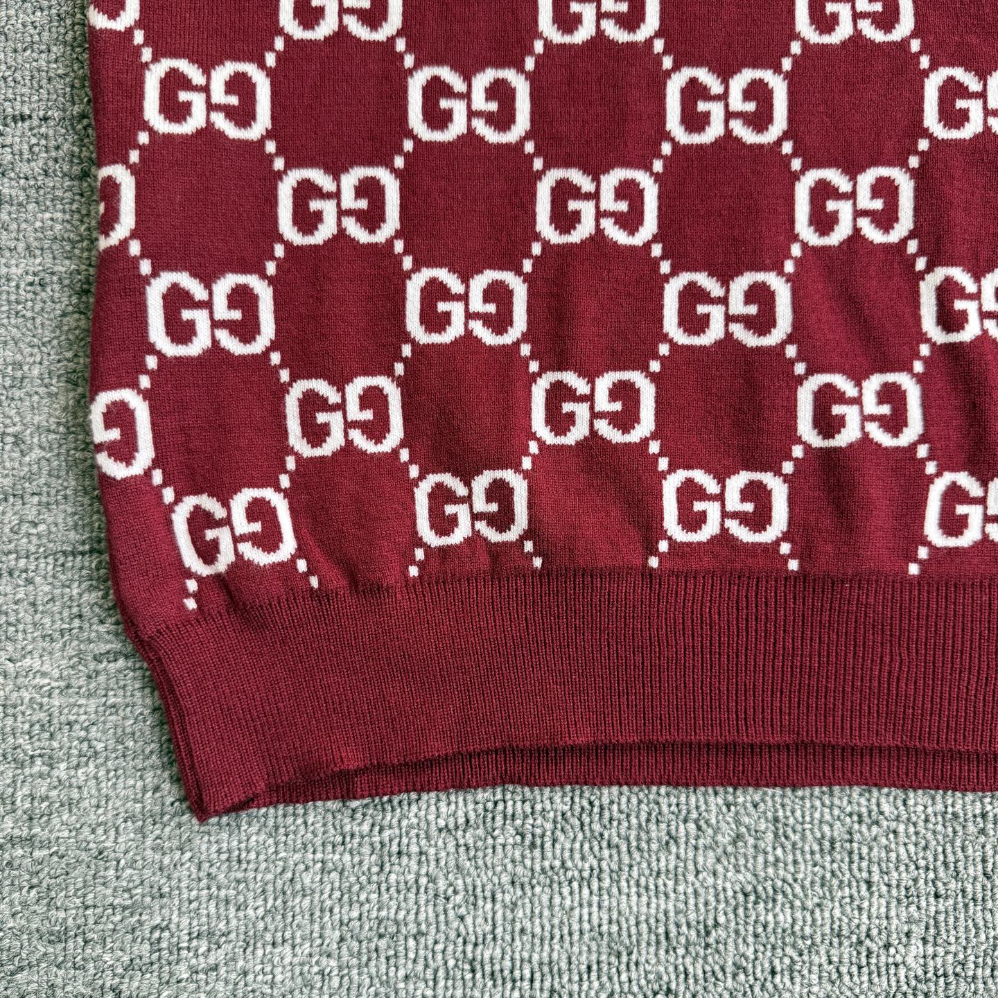 Burgundy Gucci sweater sleeve close-up with white GG diamond pattern and knit cuff