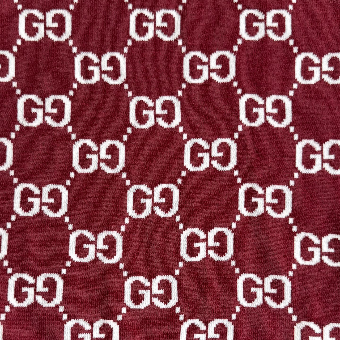 Close-up of burgundy Gucci knit fabric with white GG diamond logo pattern