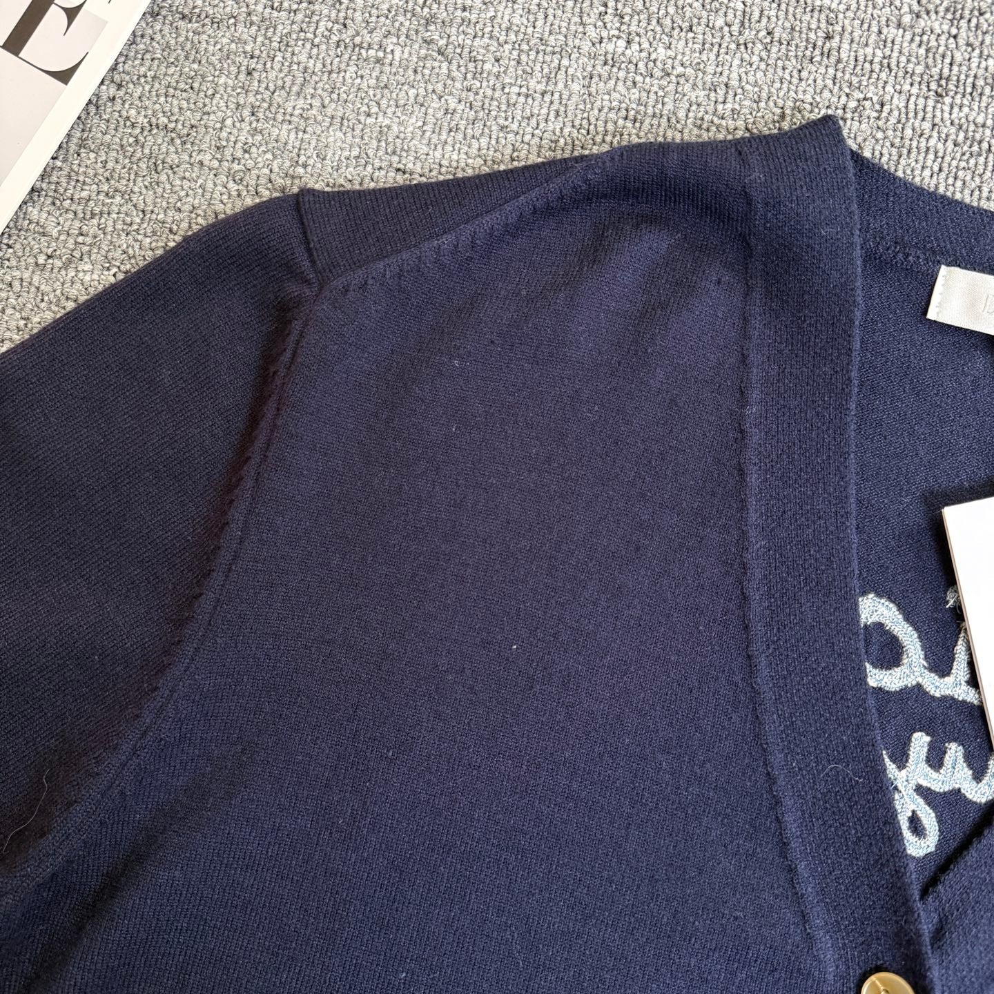 Navy Dior cardigan back yoke with ribbed trim, partial embroidered text visible