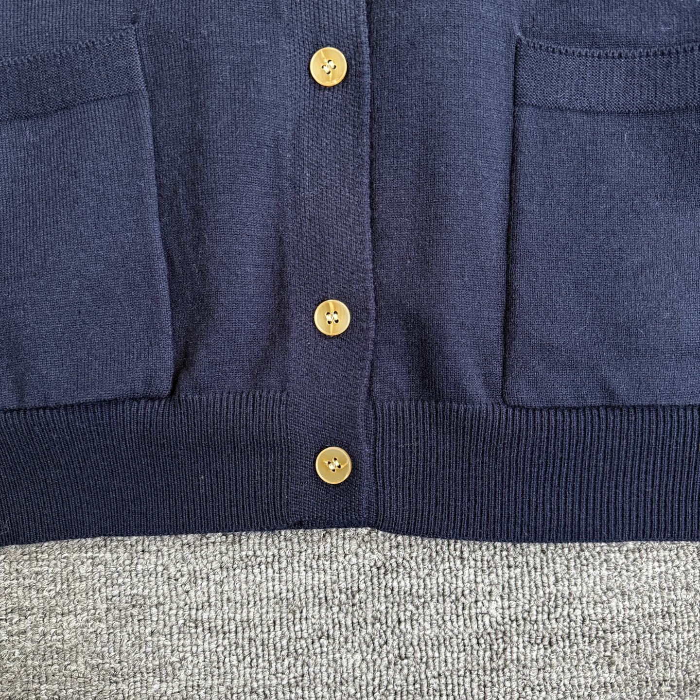 Navy Dior cardigan front with gold buttons and ribbed hem below the placket