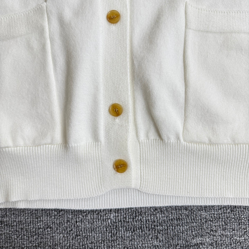 White cardigan sweater button placket with gold buttons and ribbed hem
