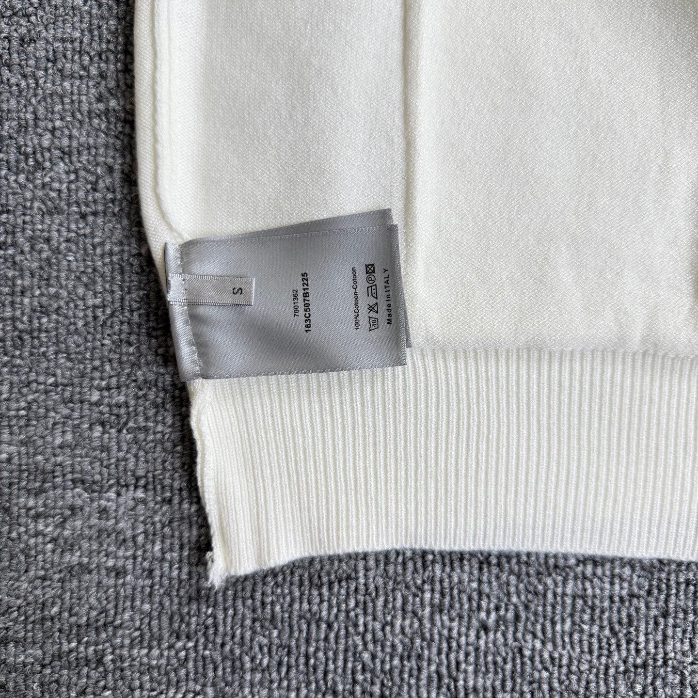 White knit cardigan sweater hem with brand size tag attached