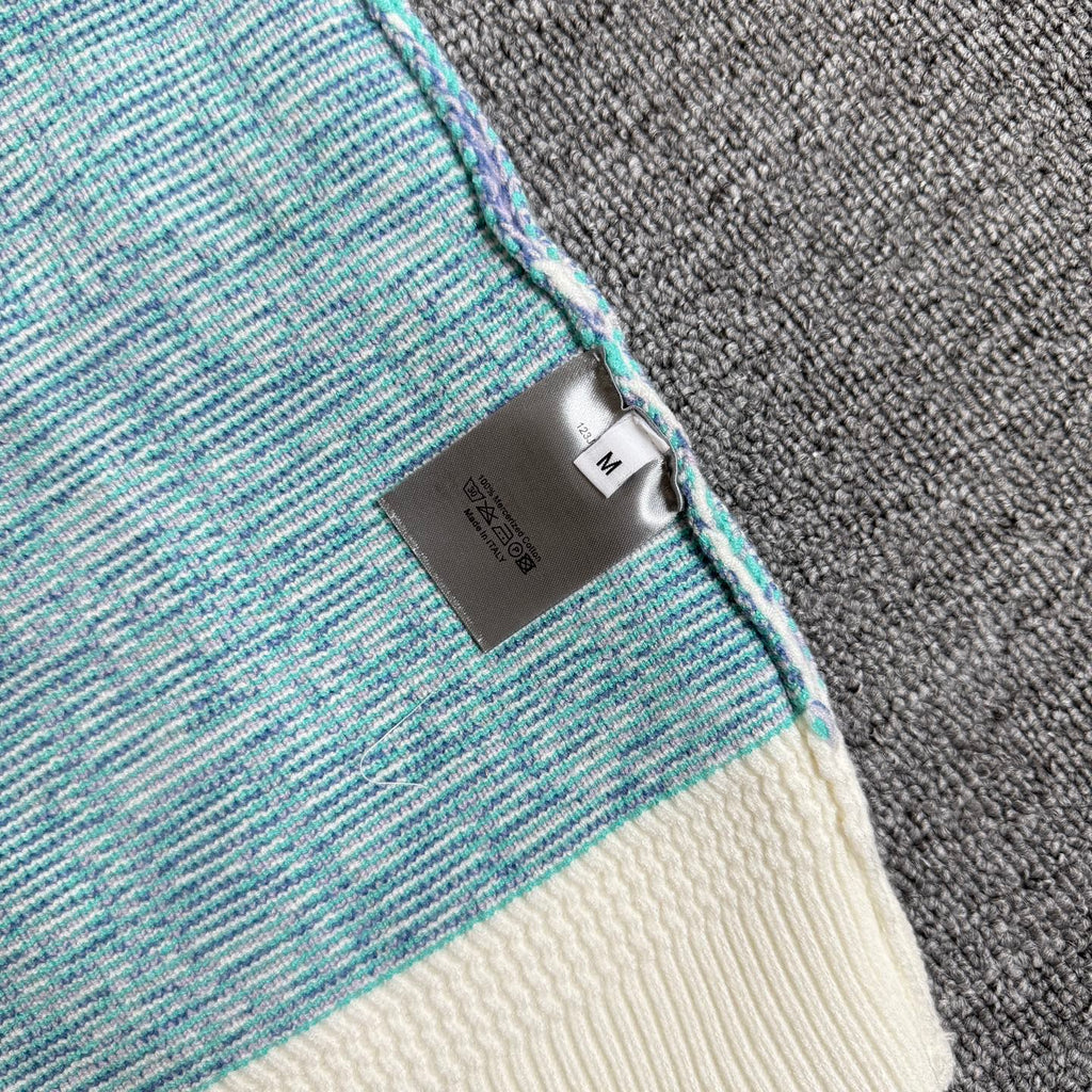Side tag and ribbed trim on light blue knit cardigan with cream cuff and hem