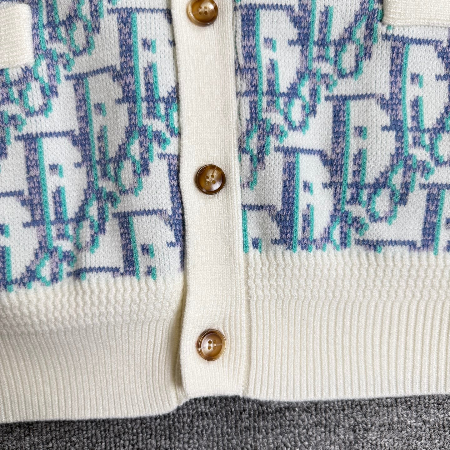 Button placket with round brown buttons and cream trim on patterned knit cardigan