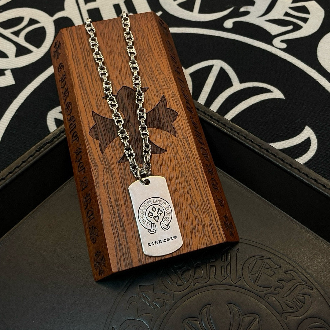 Silver-tone chain necklace with rectangular dog-tag pendant on wooden stand