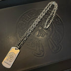 Silver-tone chain necklace with dog-tag pendant and embossed symbols