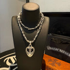 Layered silver-tone chain necklace with heart pendant on black bust display