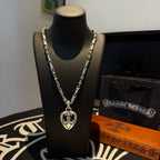 Silver-tone chain necklace with heart locket pendant, layered design on display stand