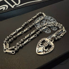 Layered silver-tone charm necklaces with heart pendant on black jewelry box