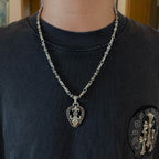 Silver-tone heart pendant necklace with chain on dark crewneck T-shirt