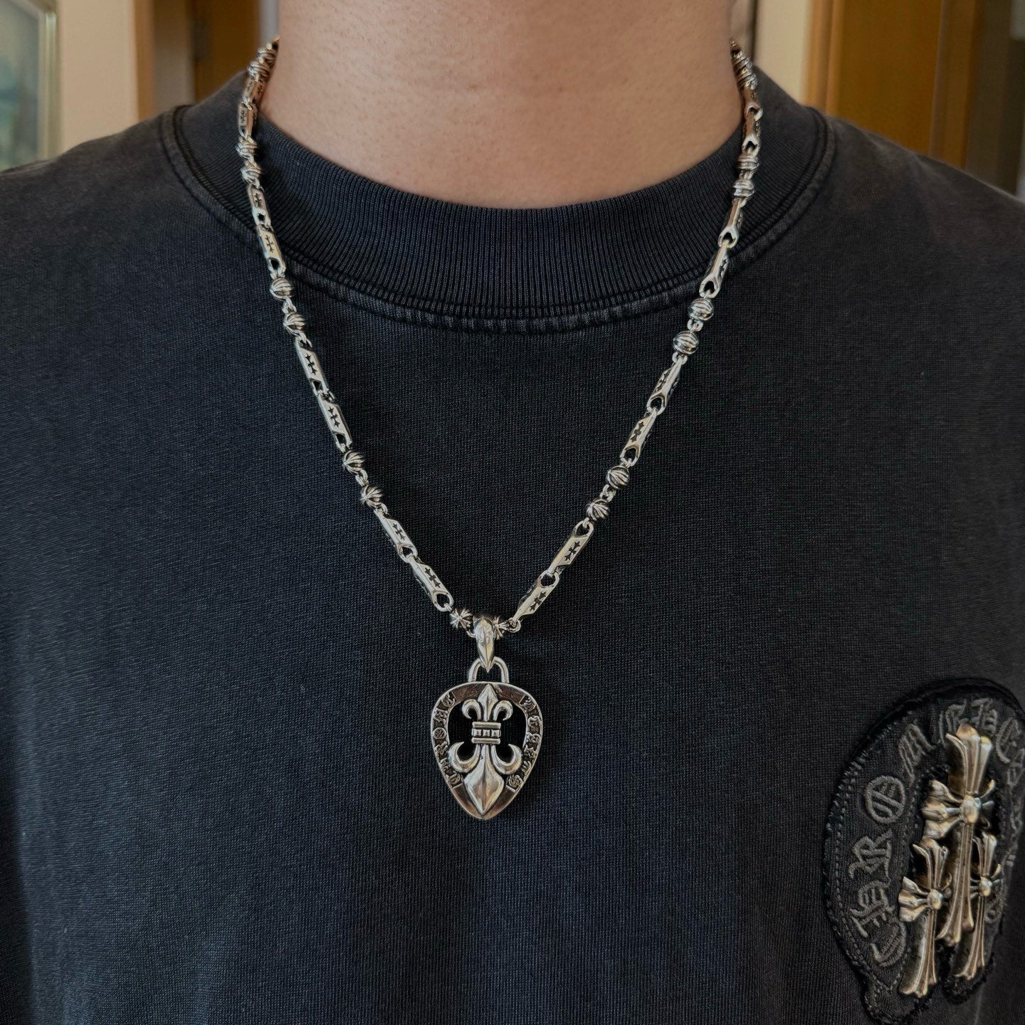 Silver-tone heart pendant necklace with chain on dark crewneck T-shirt