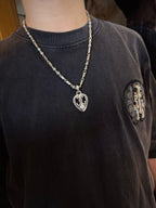 Silver-tone heart pendant necklace with chain on dark crewneck T-shirt