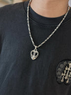 Silver-tone chain necklace with heart pendant on dark crewneck T-shirt neckline