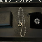 Silver-tone pendant necklace with round medallion charm on a black box