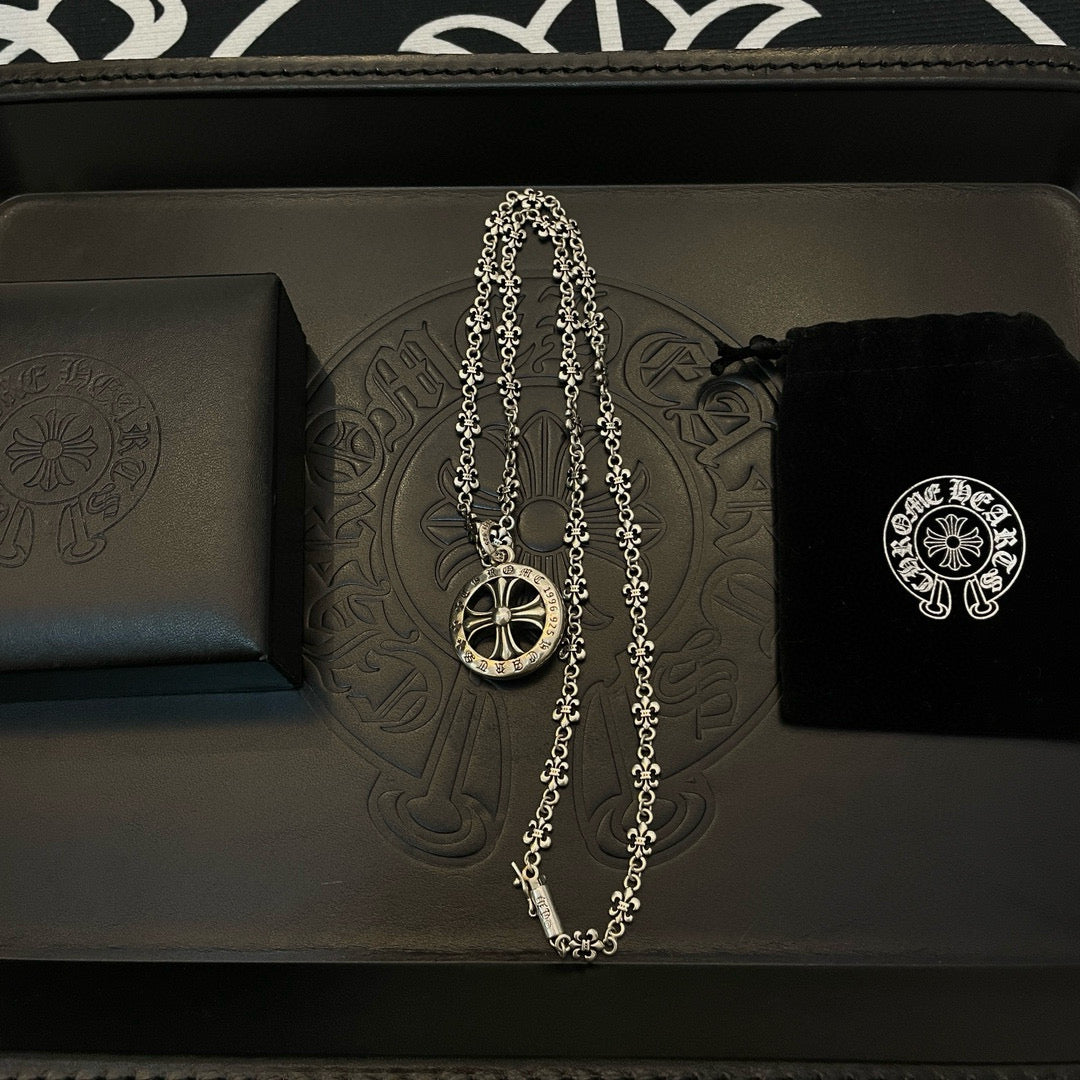 Silver-tone pendant necklace with round medallion charm on a black box
