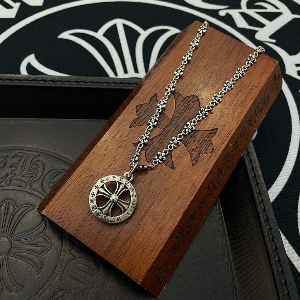 Round medallion pendant necklace with silver chain on a wooden display block
