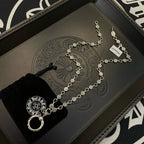 Silver-tone chain necklace with repeating coin charms and large ring pendant