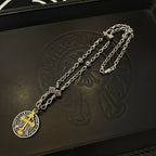 Silver-tone chain necklace with round pendant and gold cross on a black jewelry box