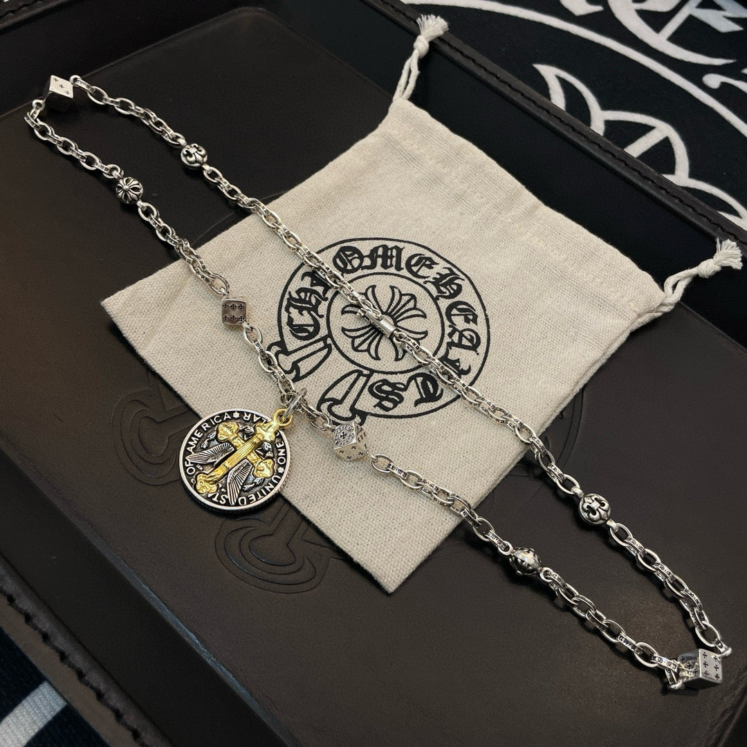 Silver-tone chain necklace with round gold-cross pendant on a beige fabric gift pouch