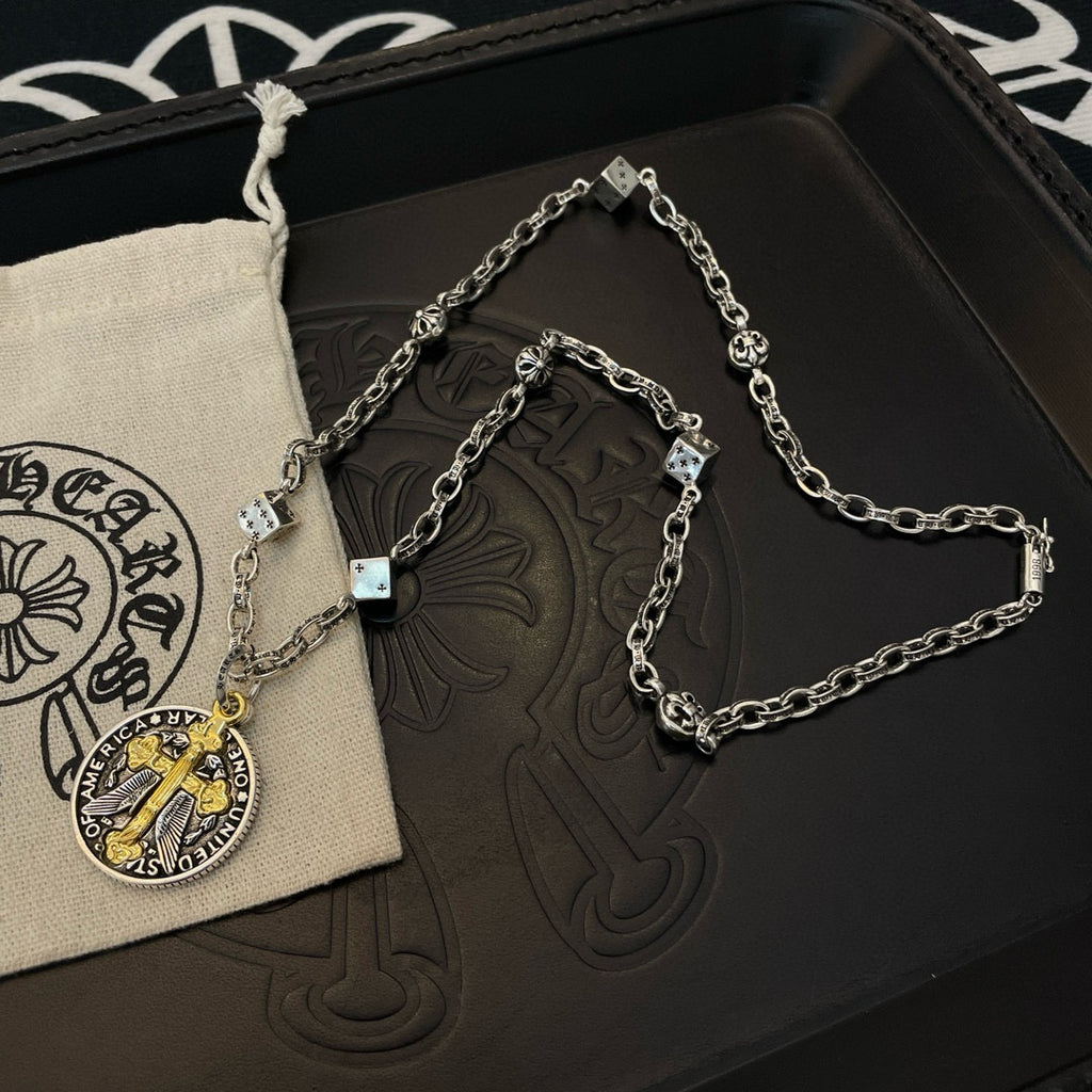 Silver-tone chain necklace with round gold-cross pendant on a black tray with pouch