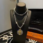 Silver-tone chain necklace with round gold-cross pendant on a black stand