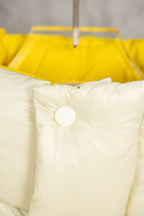 Cream puffer jacket hood area with white snap buttons and yellow inner hood