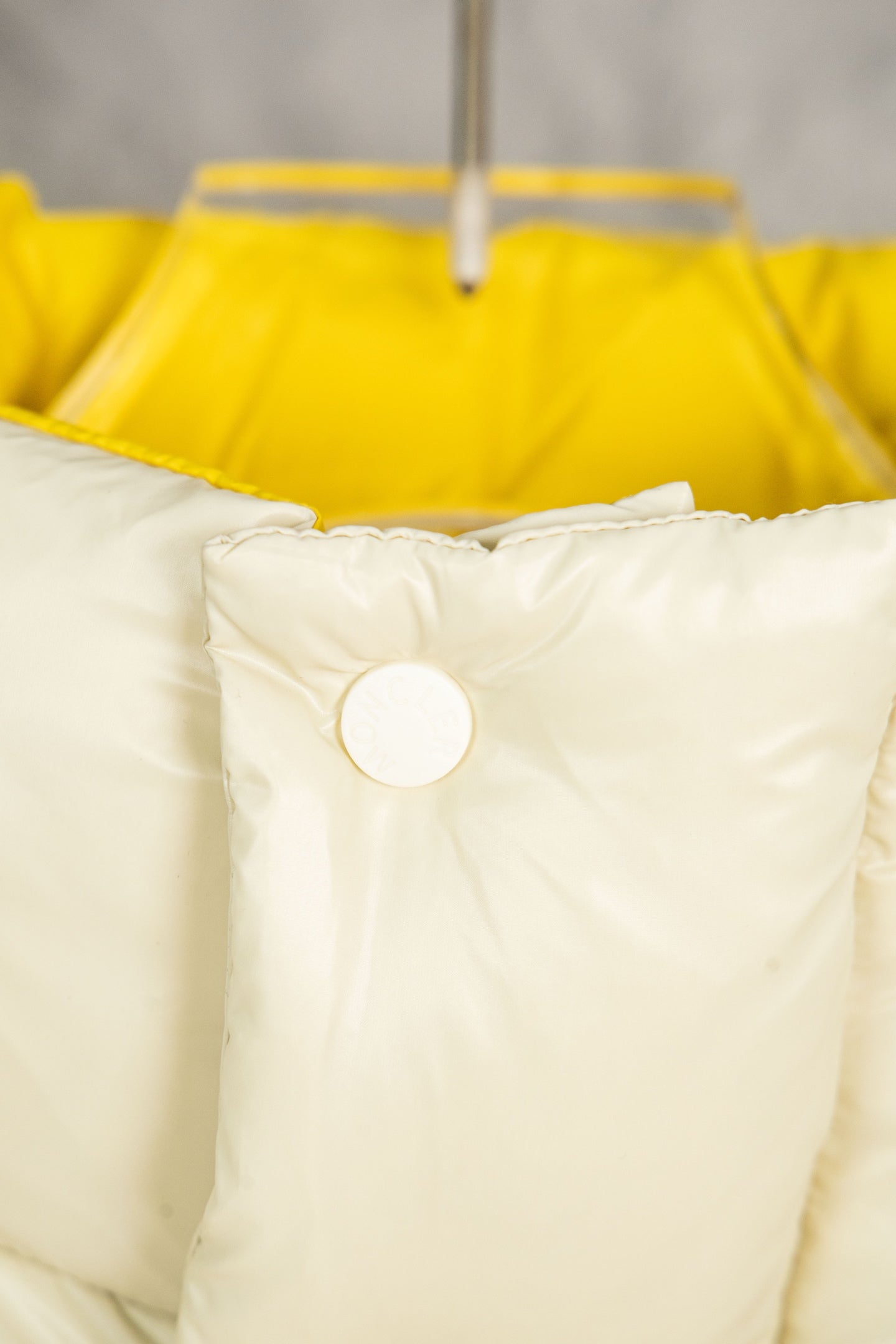 Cream puffer jacket hood area with white snap buttons and yellow inner hood