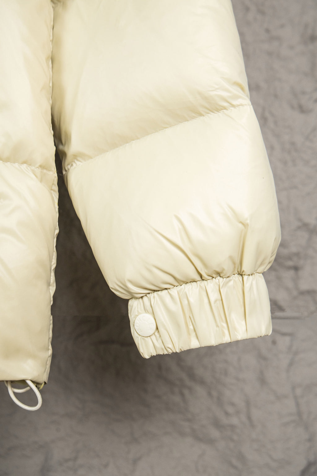 Cream puffer jacket cuff with gathered elastic and snap closure