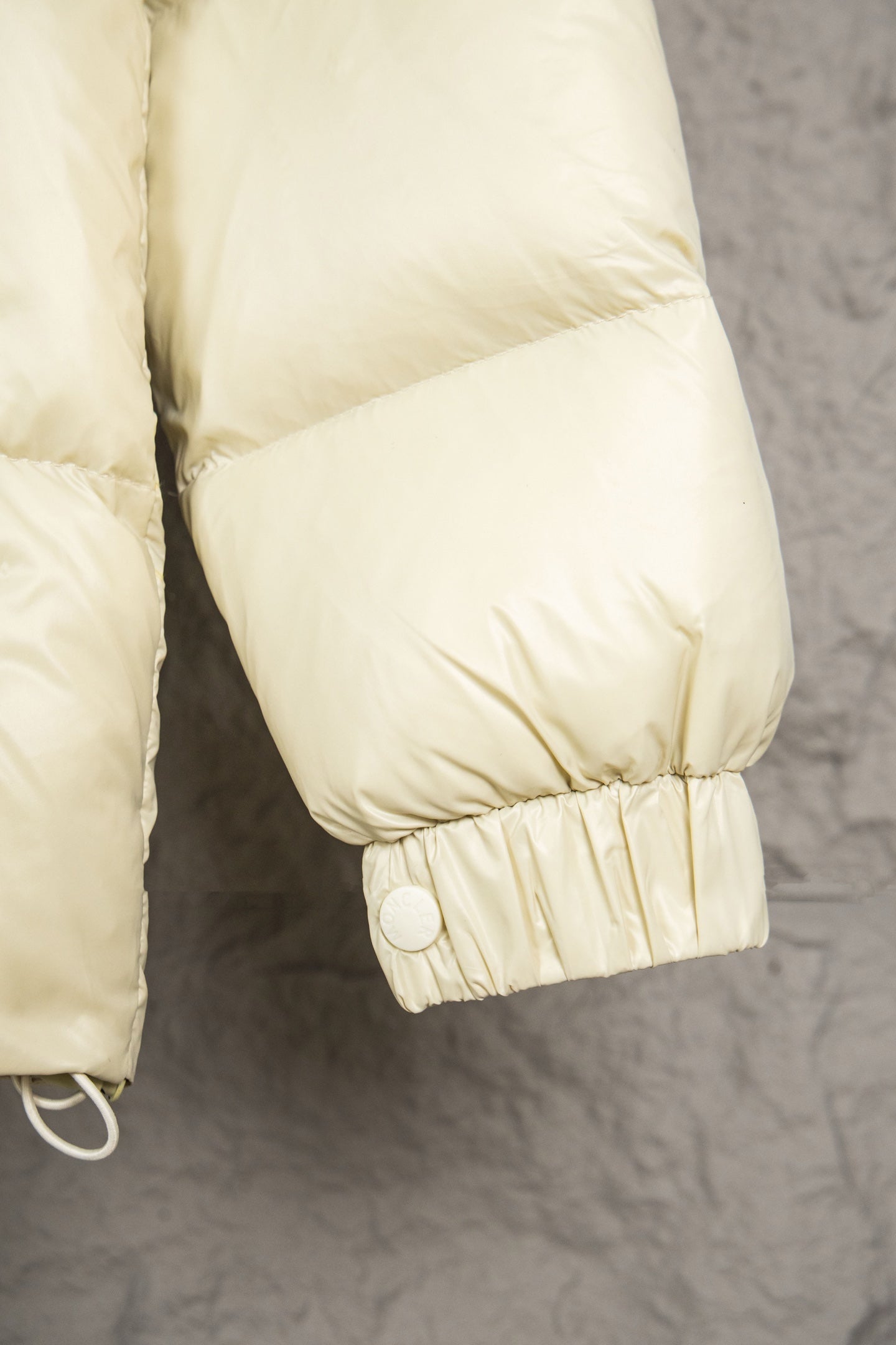 Cream puffer jacket cuff with gathered elastic and snap closure
