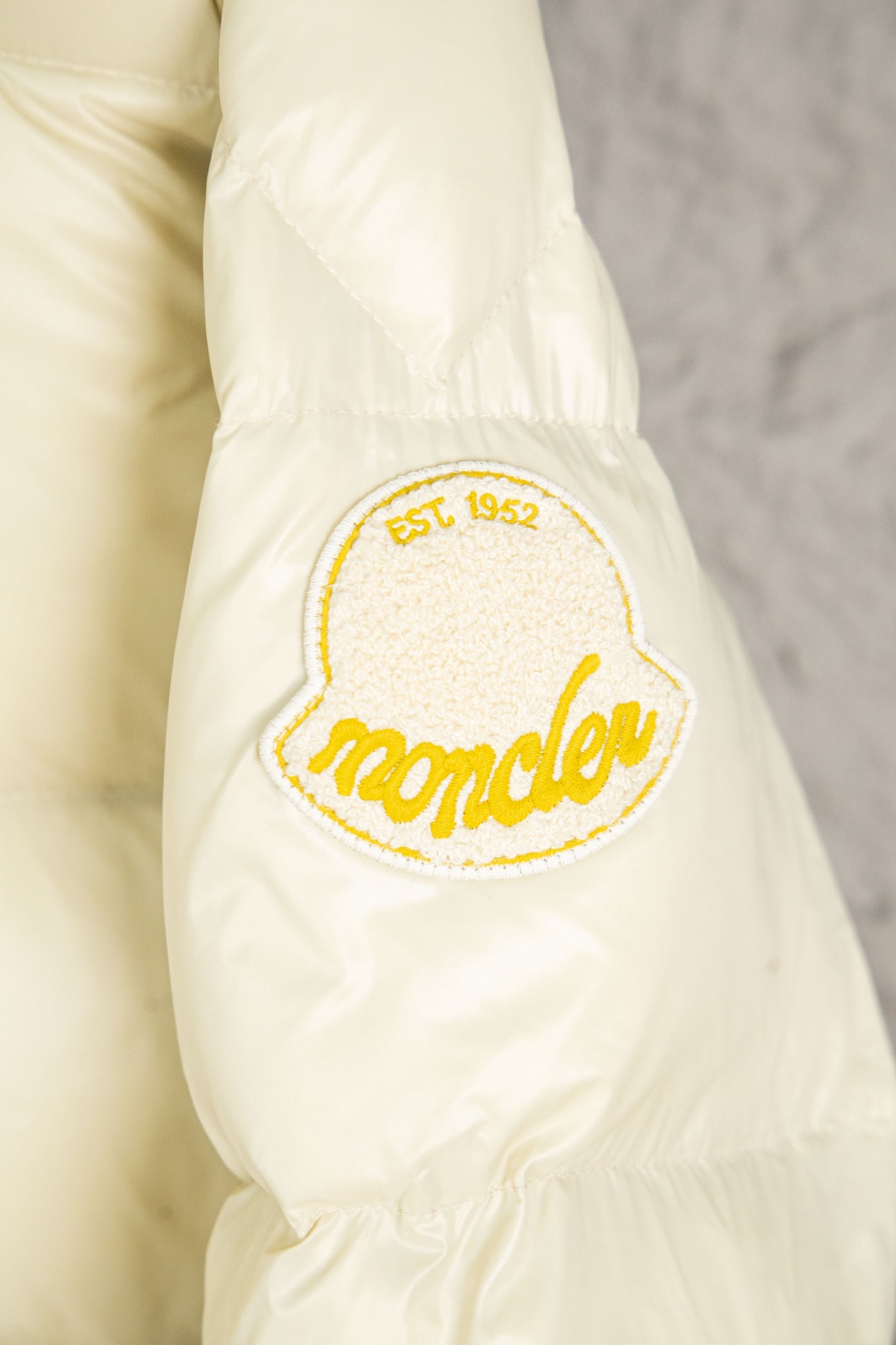 Cream Moncler sleeve with embroidered crest patch and yellow outline