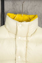 Cream puffer jacket with snap placket, high collar, and yellow hood lining
