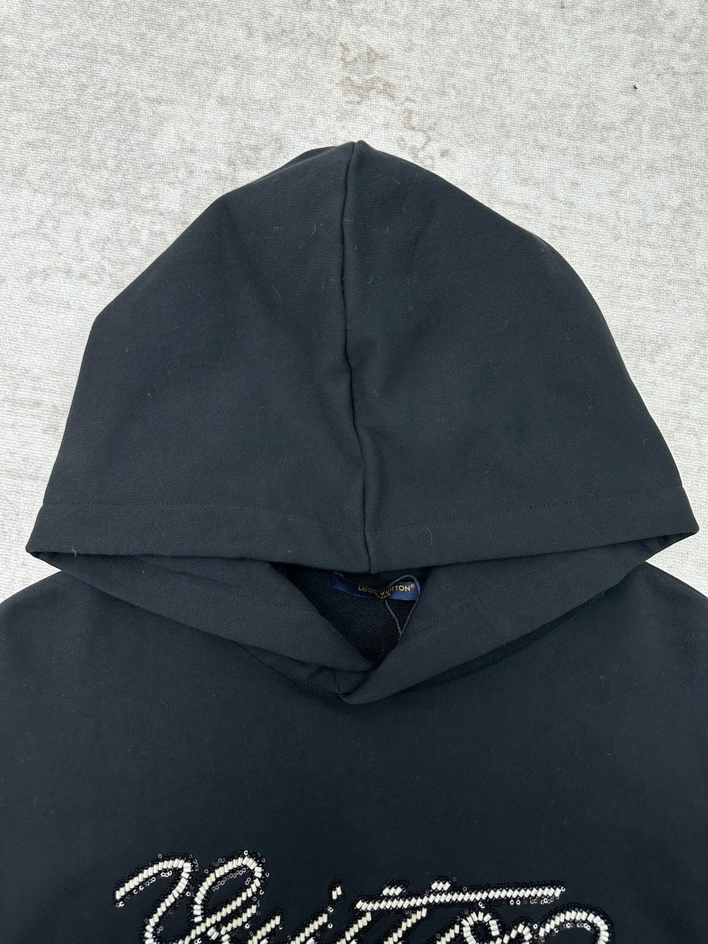 Louis Vuitton black hoodie close-up with sparkly script logo on the chest