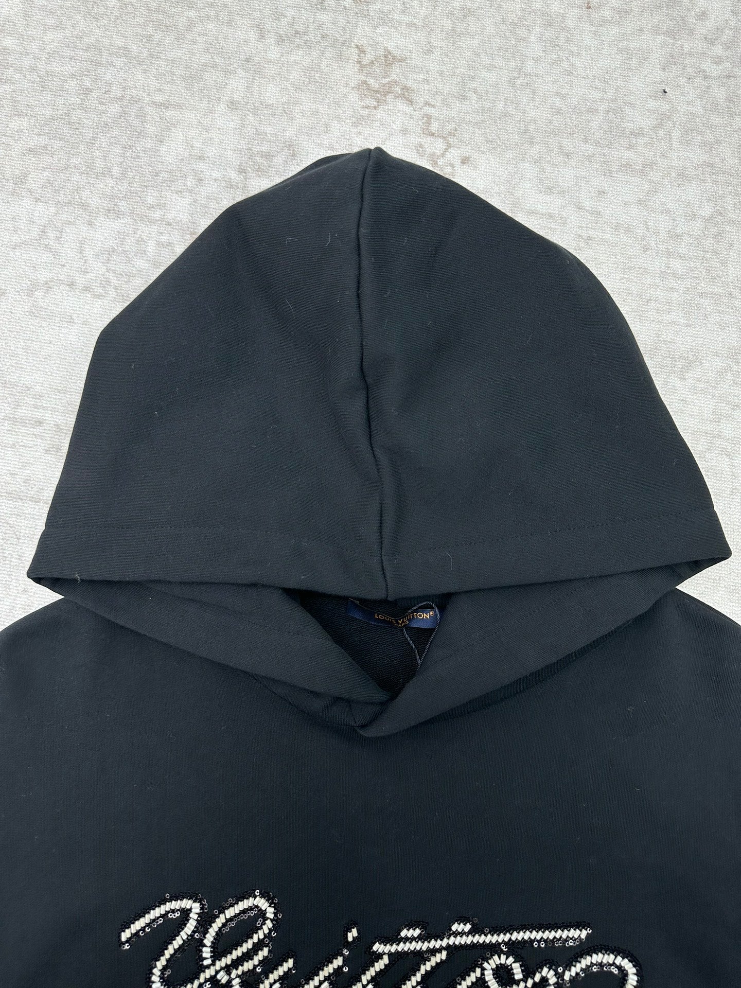 Louis Vuitton black hoodie close-up with sparkly script logo on the chest