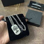 Chrome accessories necklace held in hand: silver chains with dog-tag fleur-de-lis pendants