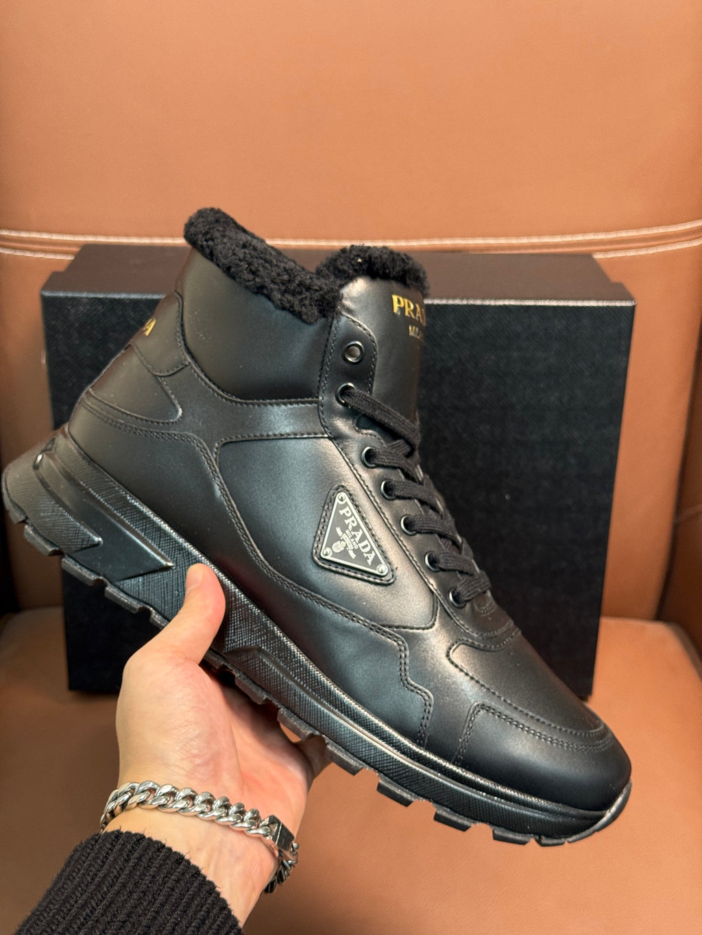 Prada lace-up boot close-up with dark leather, faux-fur collar, and logo patch