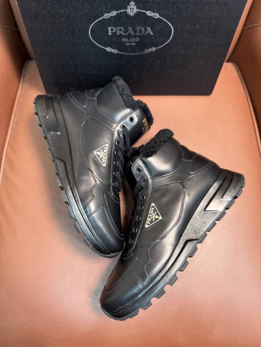 Prada lace-up boots with dark leather upper, faux-fur lining, and side logo emblem