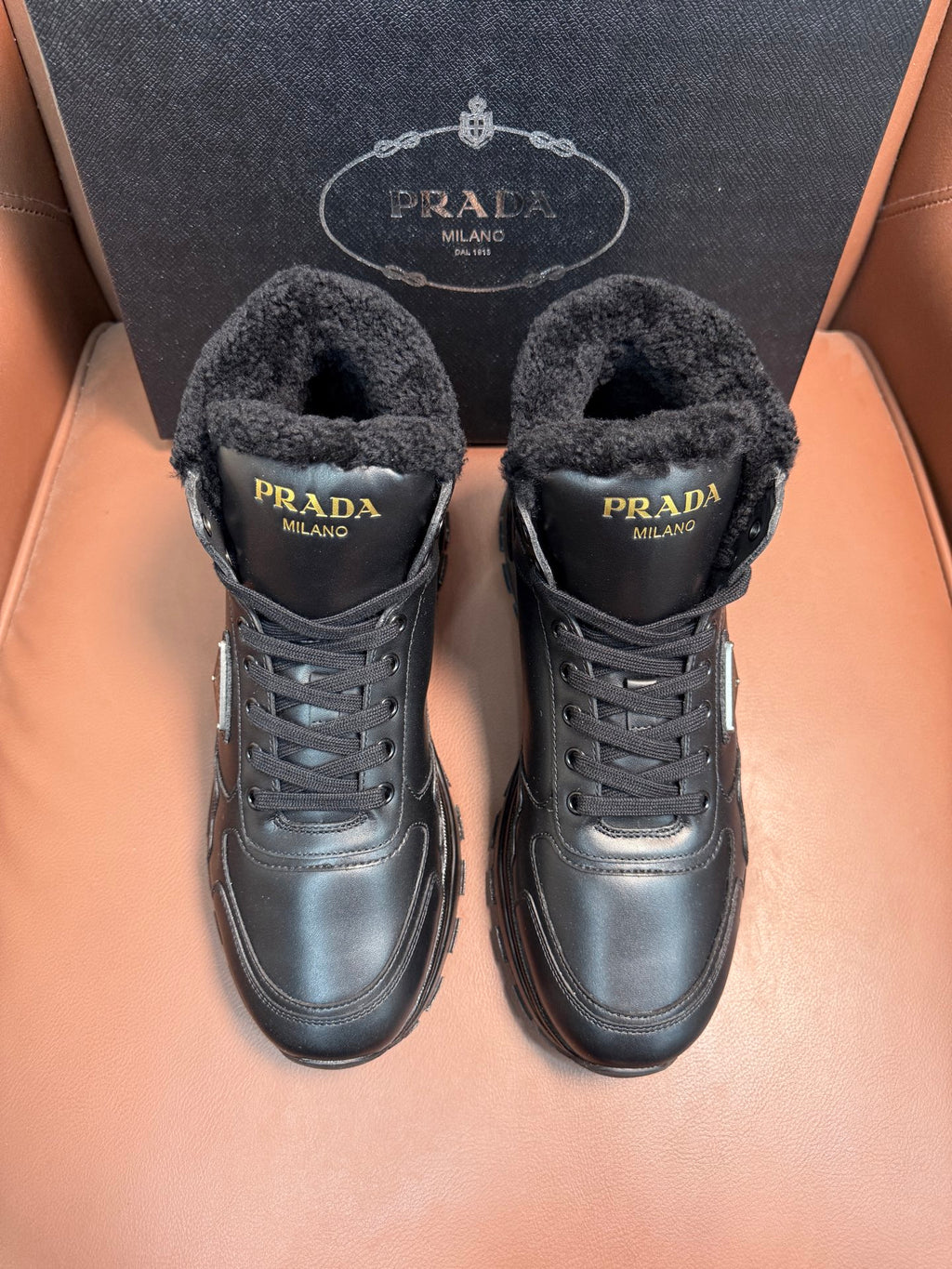 Prada lace-up winter boots with dark faux-fur lining and metal logo patch
