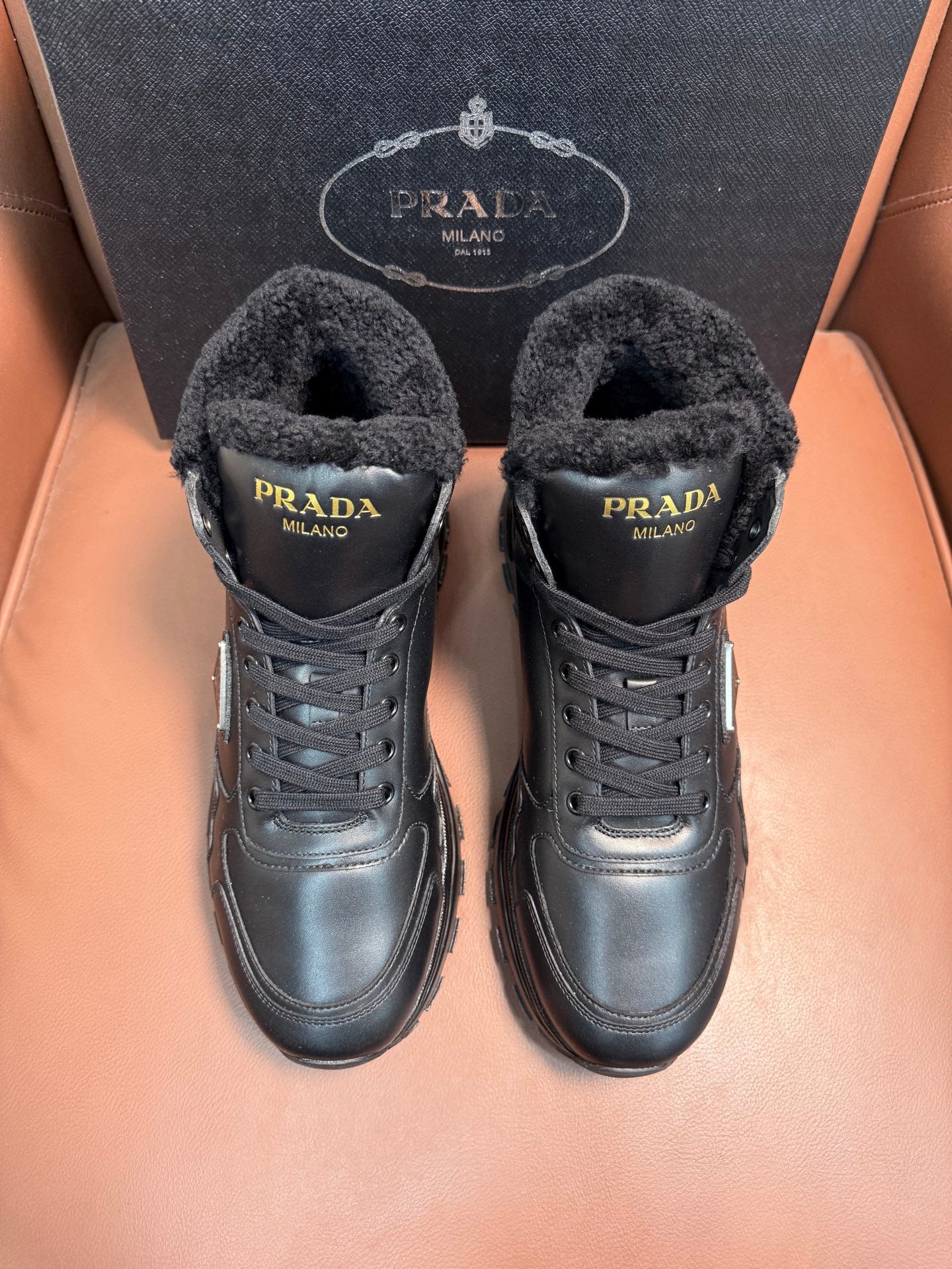 Prada lace-up winter boots with dark faux-fur lining and metal logo patch
