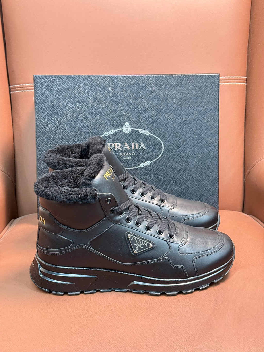 Prada lace-up boots with dark leather and faux-fur collar, shown as a pair