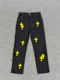 Chrome pants in dark fabric with repeating yellow cross graphics across the legs