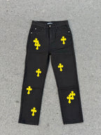 Chrome pants in dark fabric with repeating yellow cross graphics across the legs