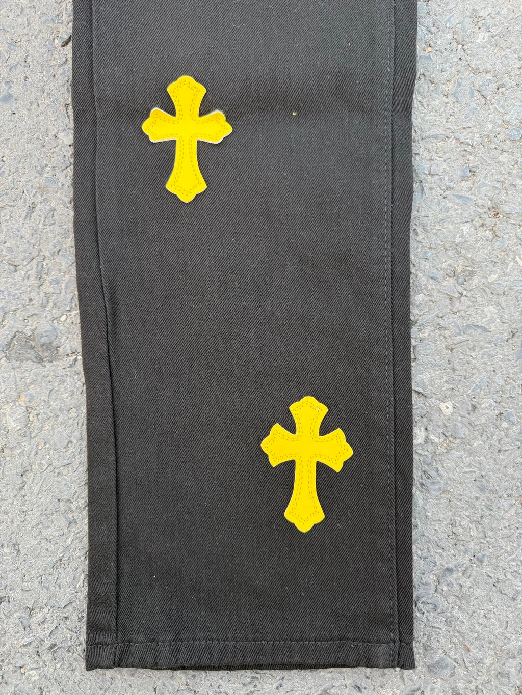 Black pants with yellow cross patches on the side hem area